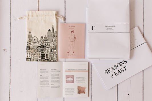 A picture of all the sustainable elements that make up Seasons of East paper patterns including an Oeko-Tex cotton drawstring bag featuring the London skyline and the instruction booklet made from post consumer waste and the paper pattern.