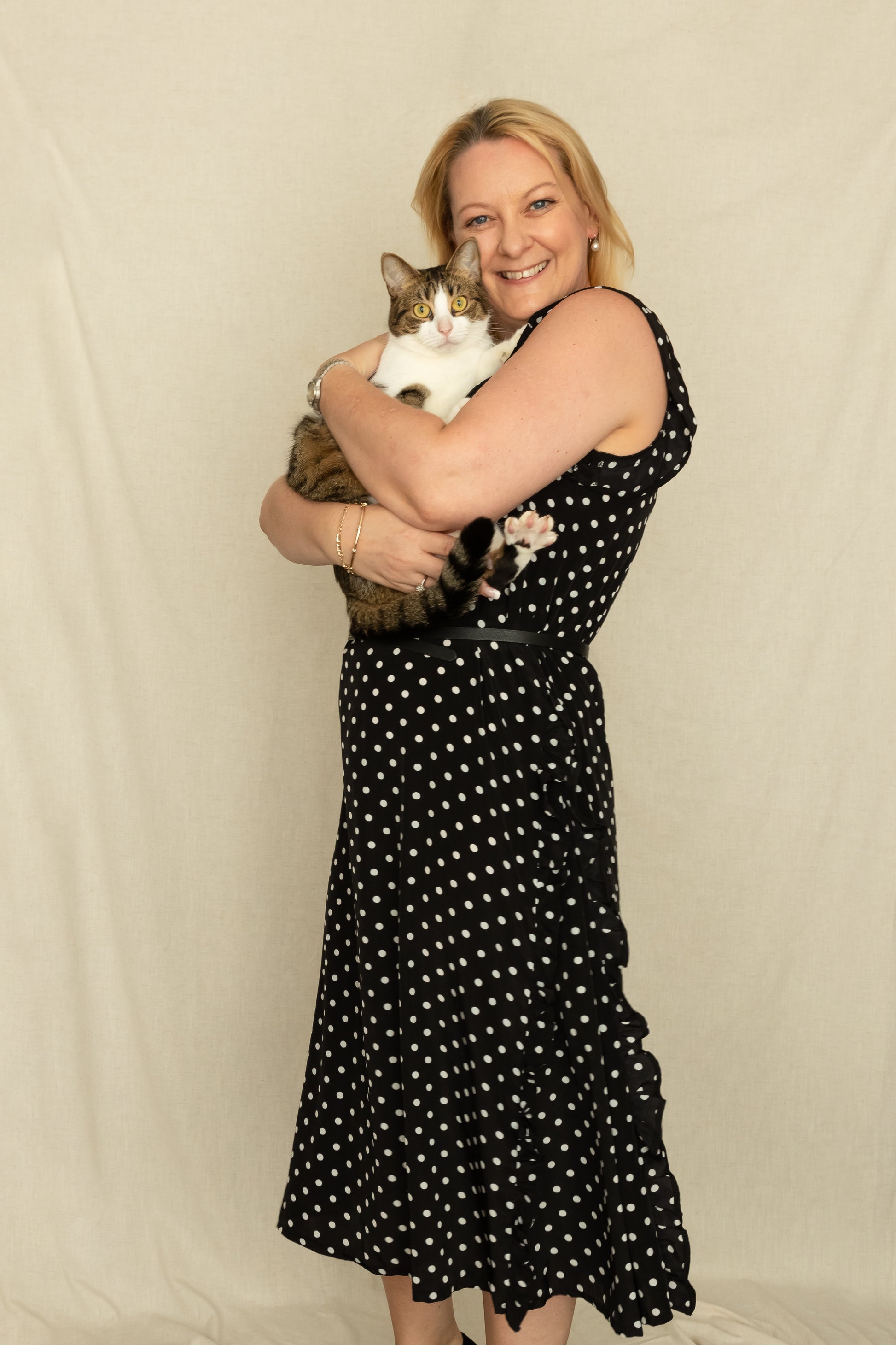 Woman holding a cat whilst wearing a black and white polka dot, vintage inspired 1920's dress with godets.