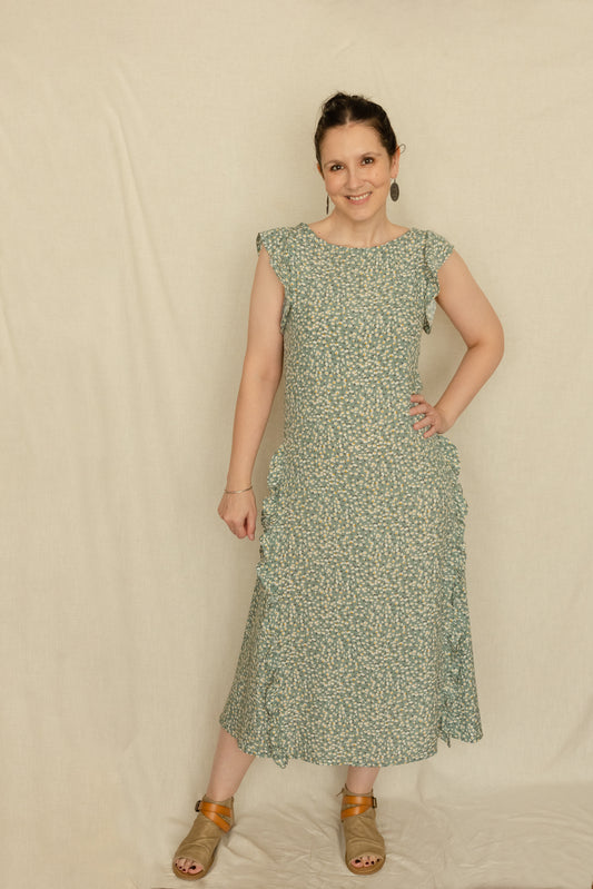 Woman wearing a vintage inspired 1920's style dress with godets and ruffles in a green fabric with white flowers.