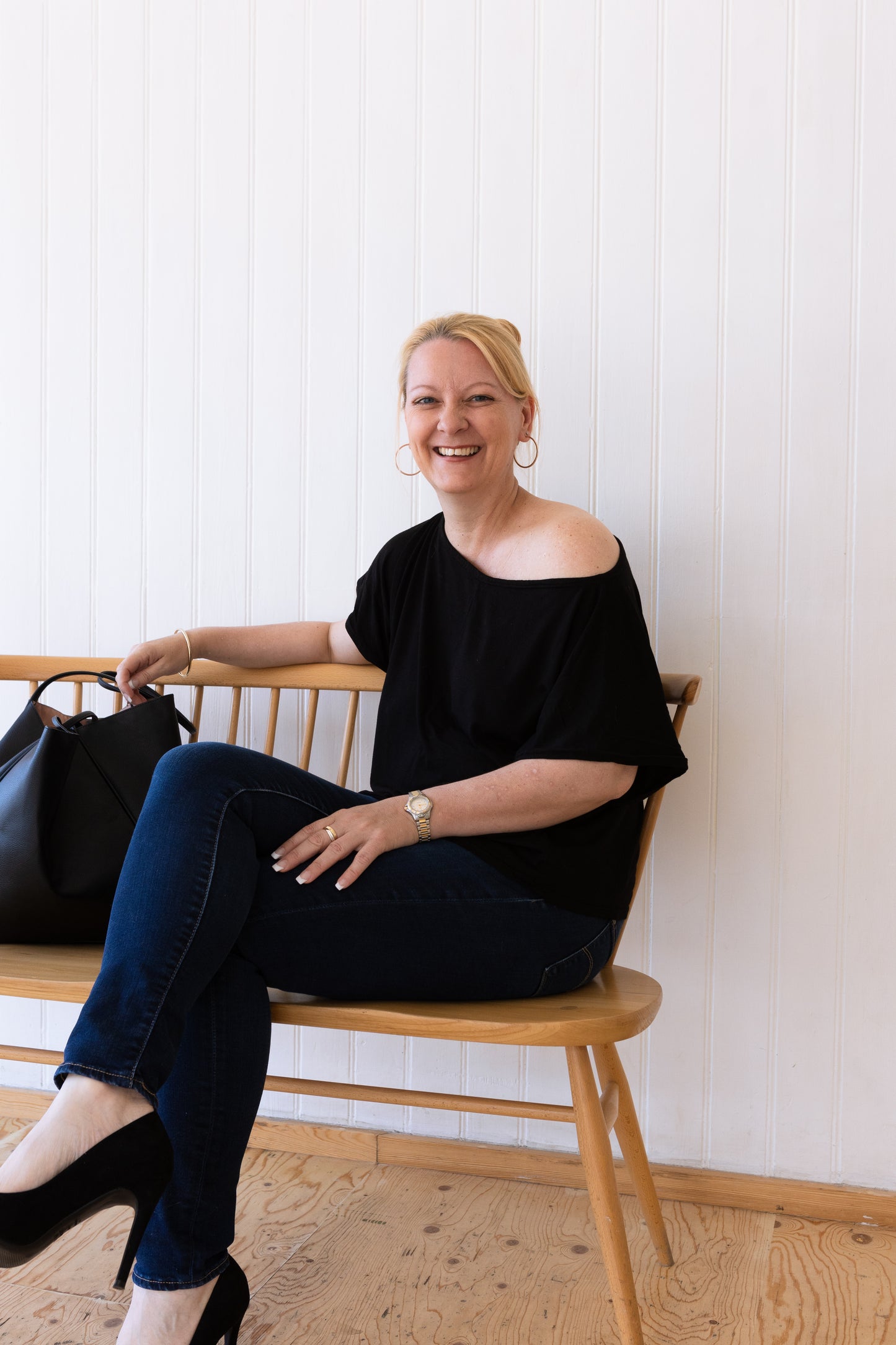 Woman sitting down wearing a black vintage inspired slouchy t-shirt and jeans.
