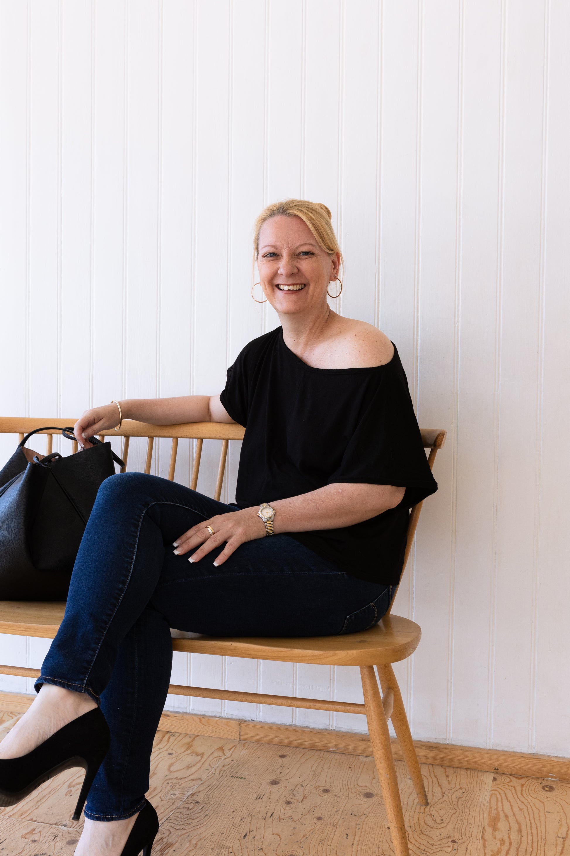 Woman sitting down wearing a black vintage inspired slouchy t-shirt and jeans.