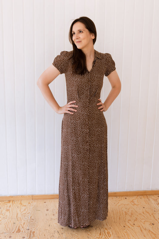 Woman wearing a vintage inspired button down maxi dress with collar, darts and pleats with hands on hips.