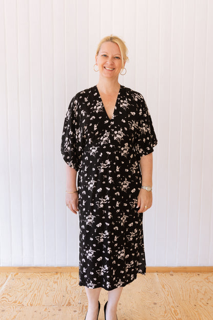 Woman wearing a vintage inspired dress with kimono sleeves in a black and white floral fabric.