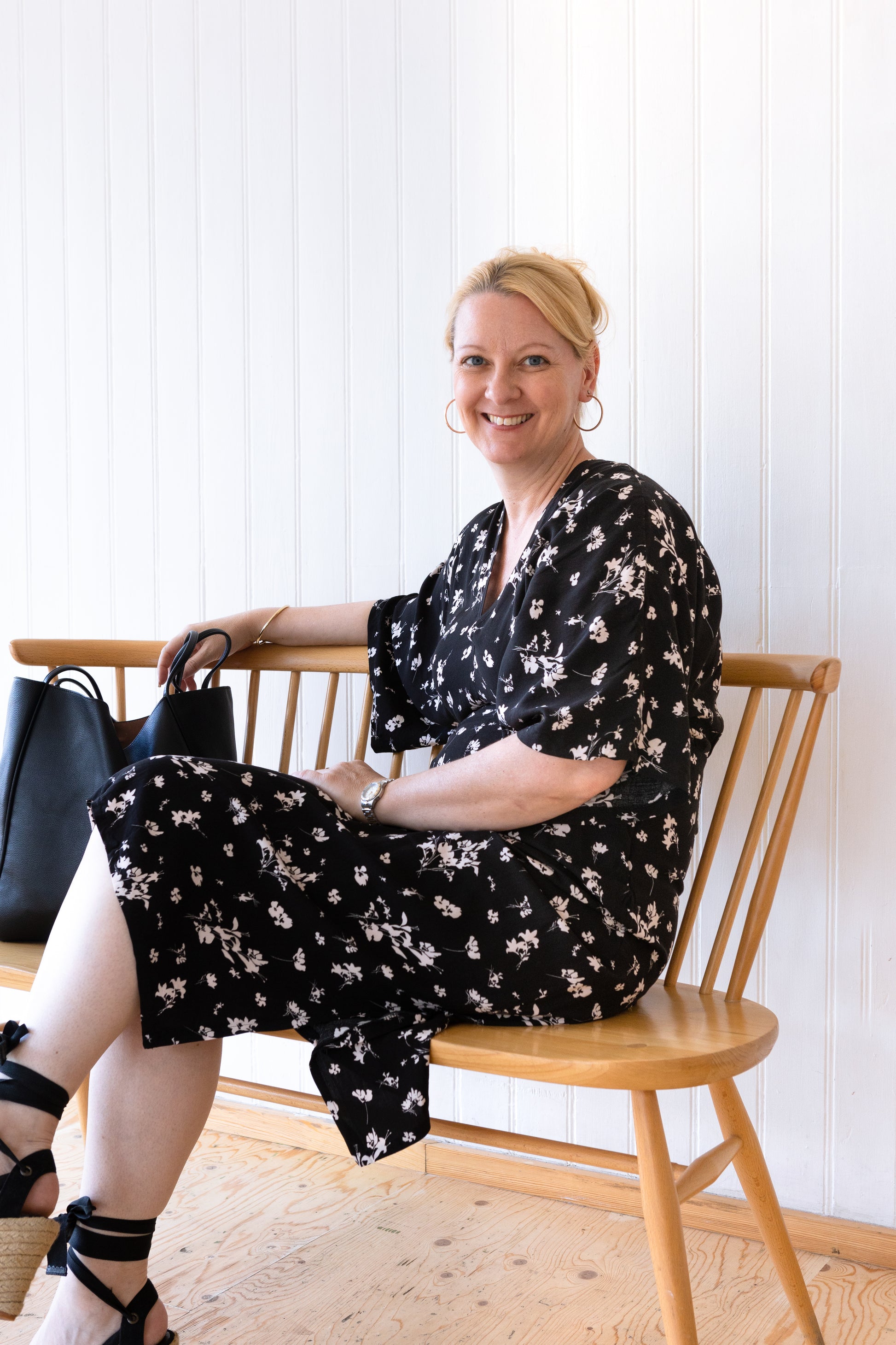 Woman sitting down in a vintage inspired black and white summer dress with kimono sleeves and side splits.