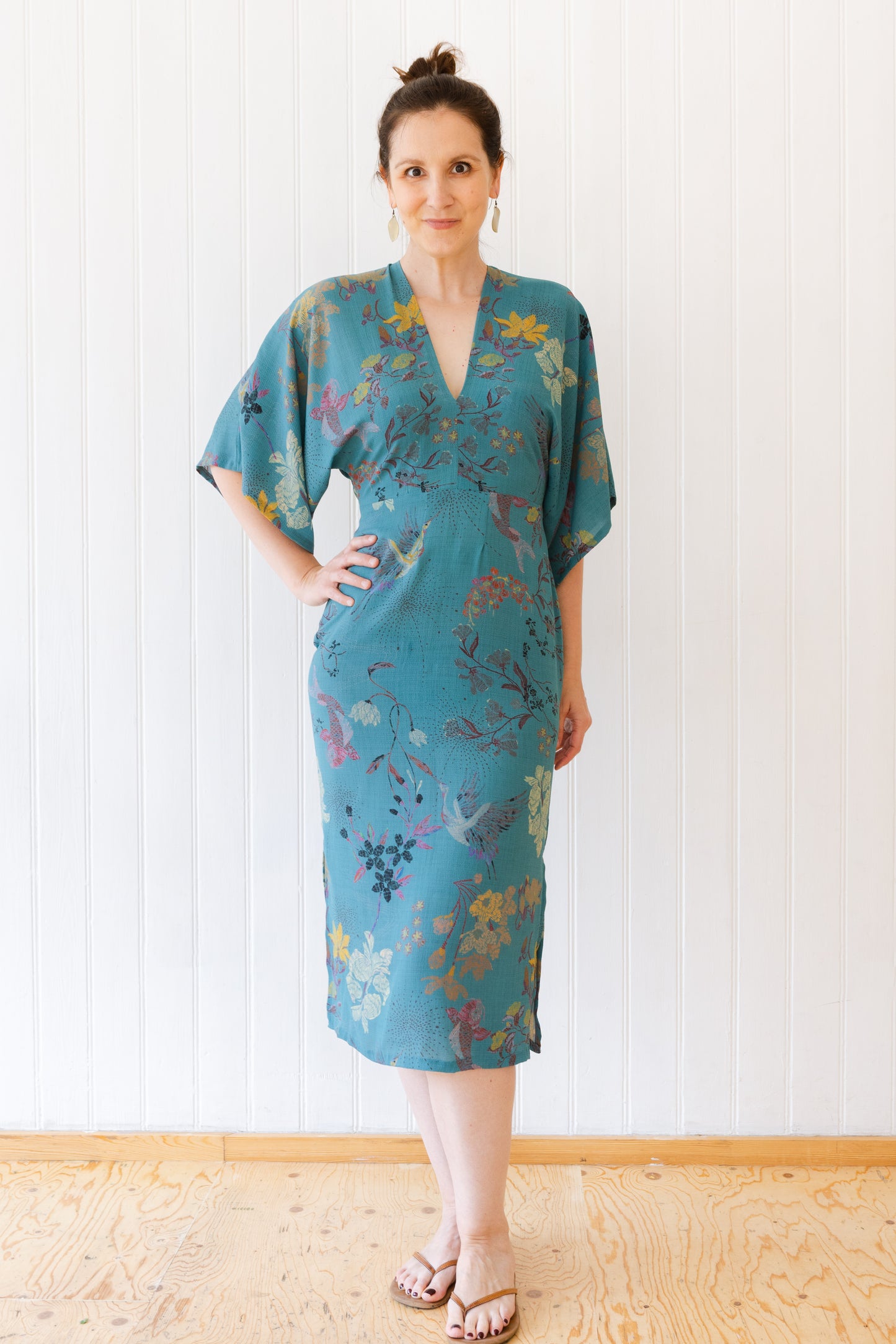 Woman wearing a vintage inspired dress with kimono sleeves in an oriental teal fabric.