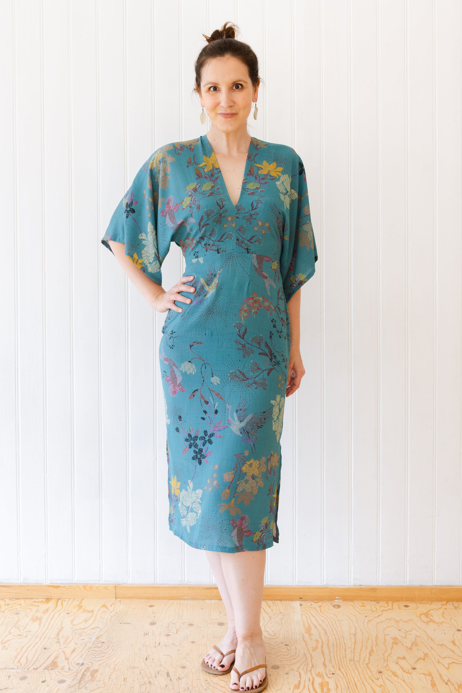 Woman wearing a vintage inspired dress with kimono sleeves in an oriental teal fabric.