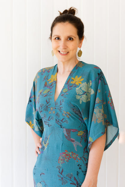 Woman wearing a vintage inspired teal dress with kimono sleeves.