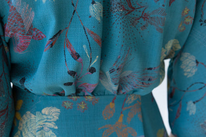 Close up showing the gathered waistline of the back bodice of a vintage inspired dress in a teal fabric featuring an oriental pattern.