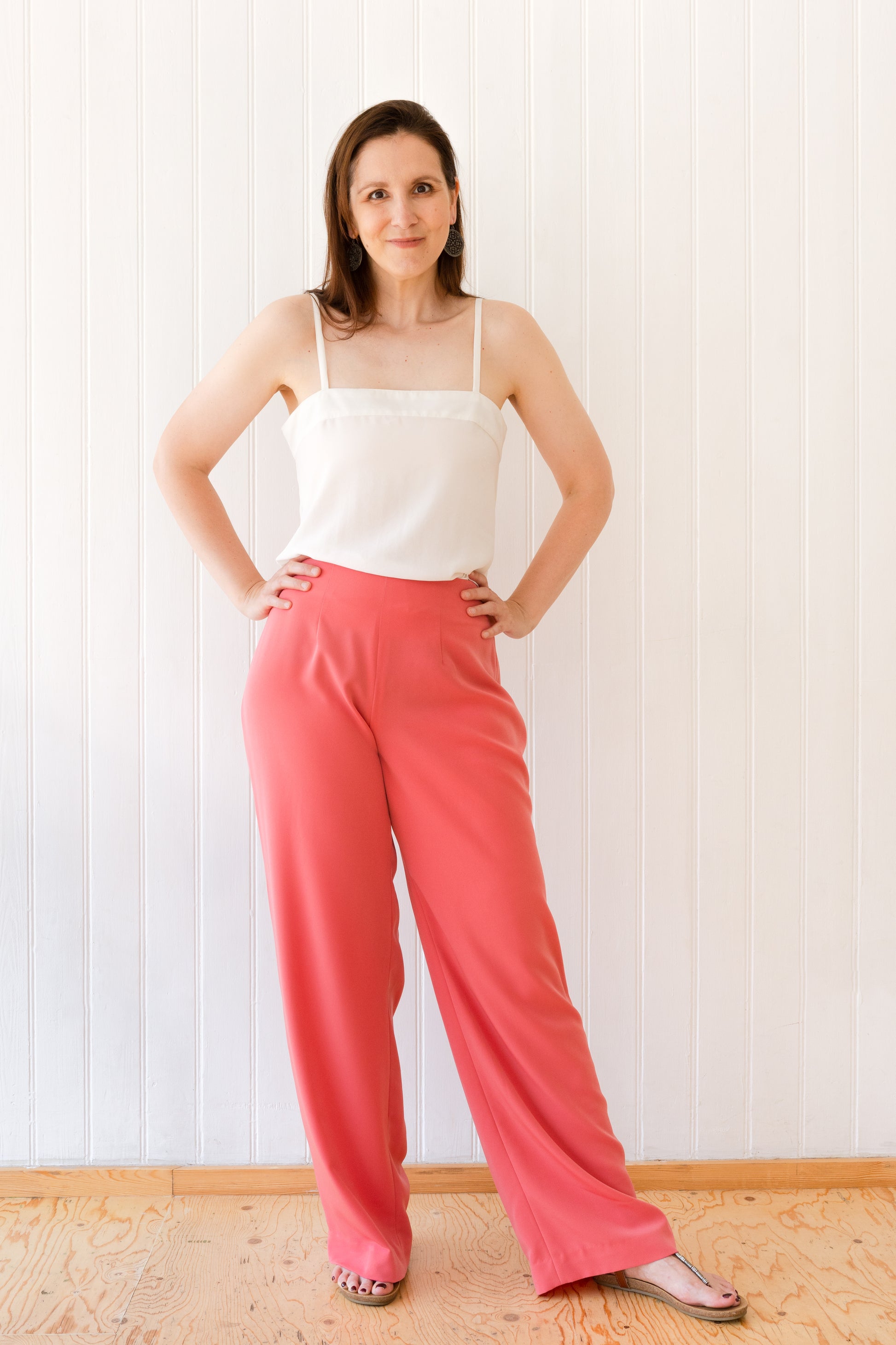 Woman wearing a pair of wide leg vintage inspired coral coloured trousers.