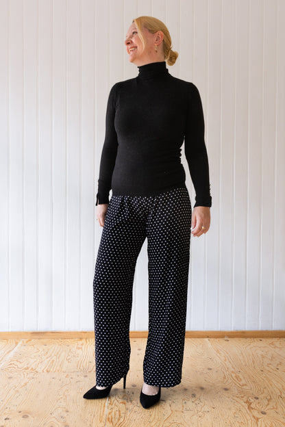 Woman wearing a pair of black and white polka dot, wide leg, vintage inspired trousers.
