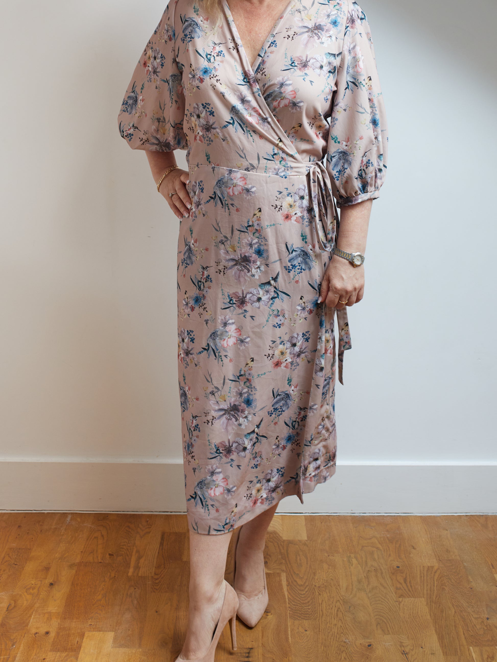Woman wearing a vintage inspired wrap dress with bishop sleeves in a light pink fabric.