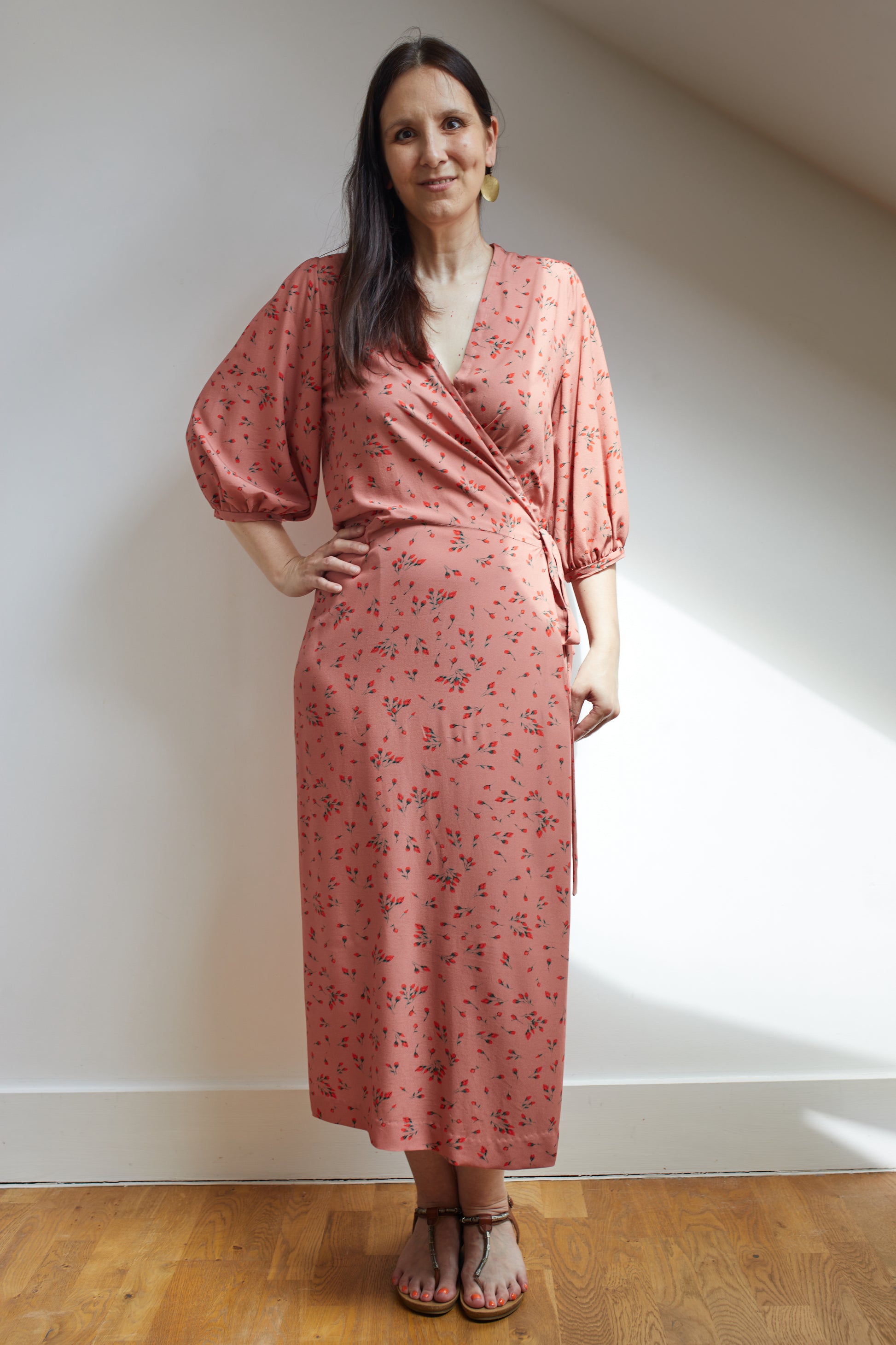 Woman wearing a vintage inspired wrap dress with bishop sleeves in a soft pink fabric.