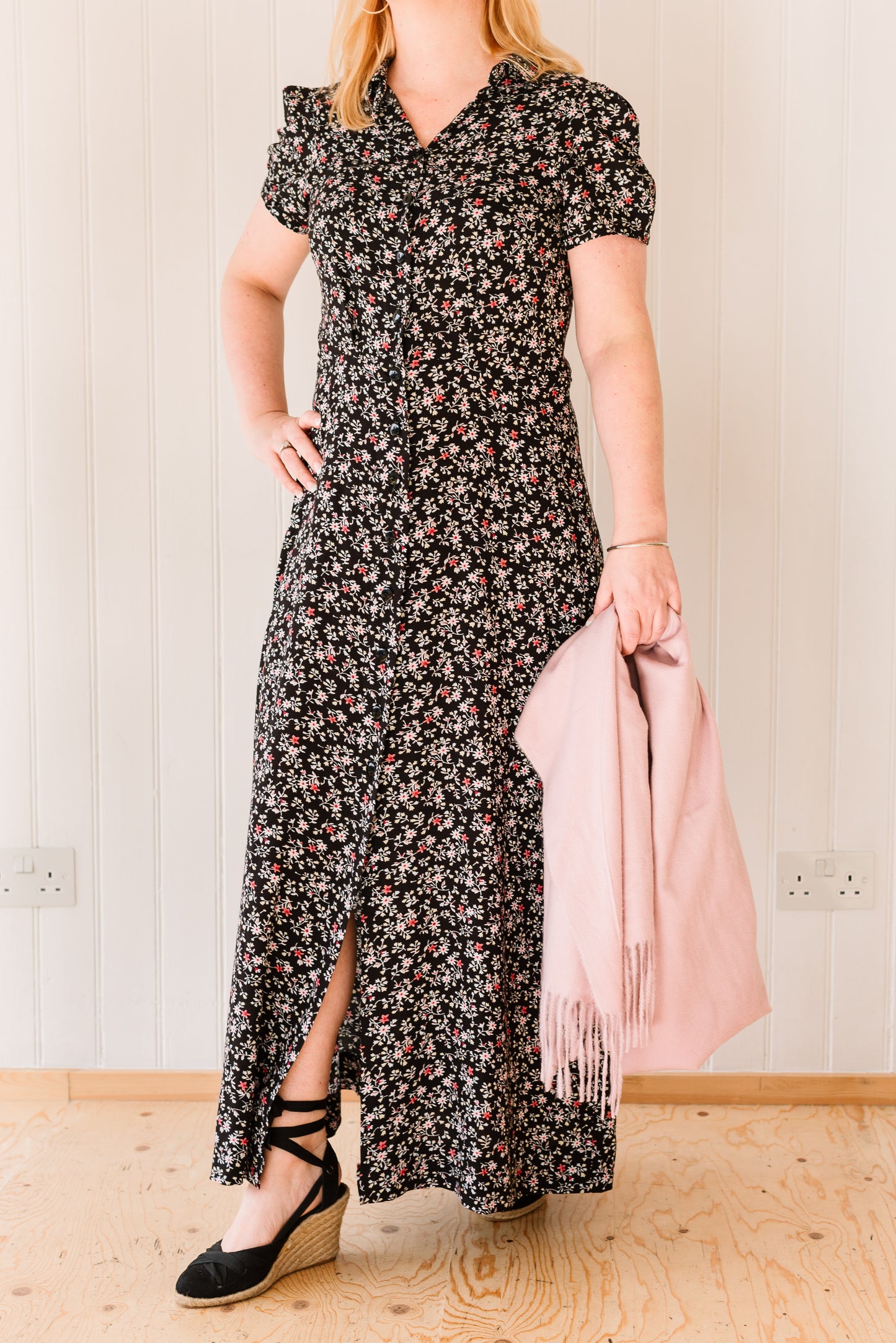 Woman wearing a vintage inspired maxi dress in a floral fabric accessorised with a pink pashmina.