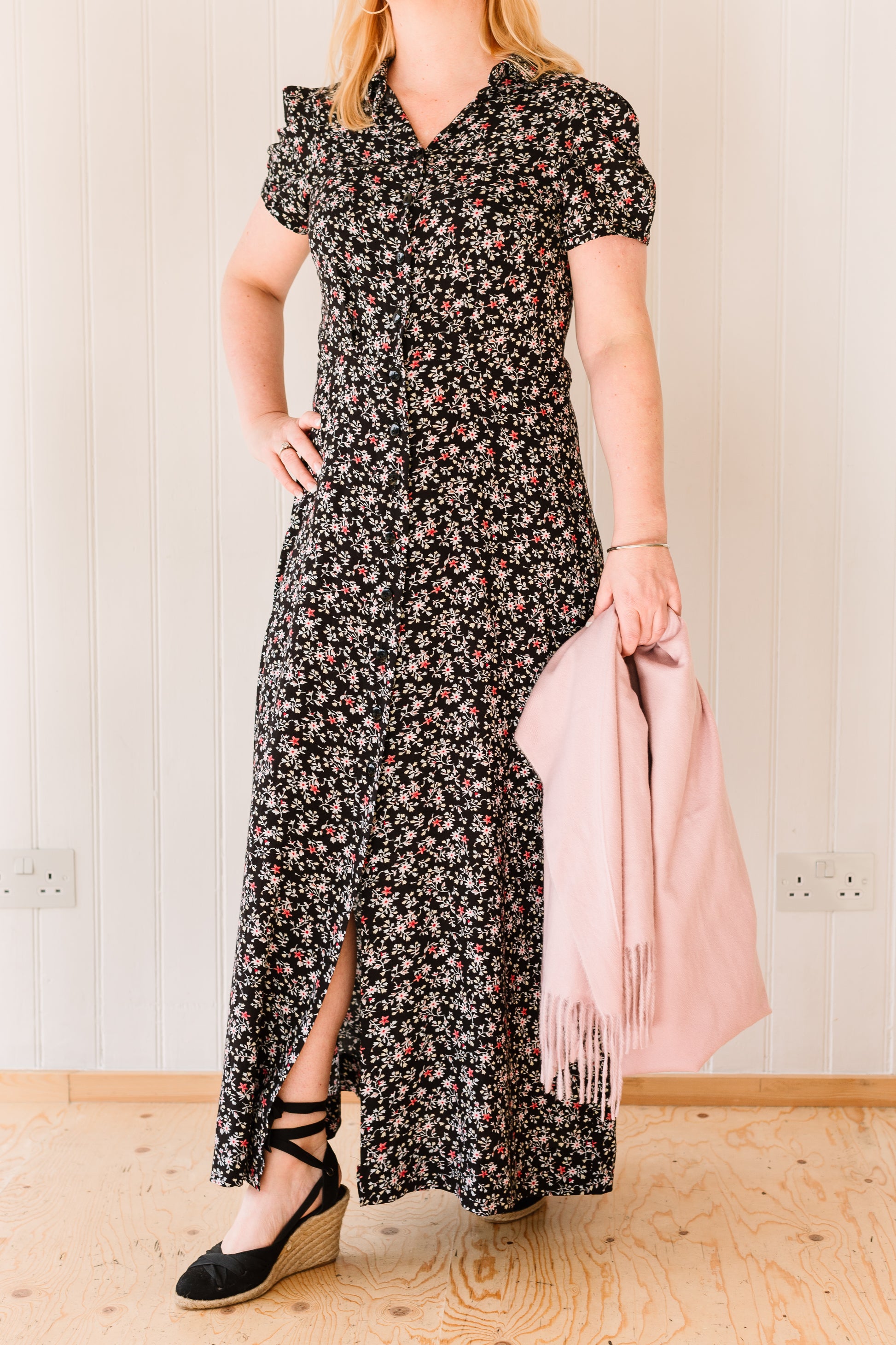 Woman wearing a vintage inspired maxi dress in a floral fabric accessorised with a pink pashmina.